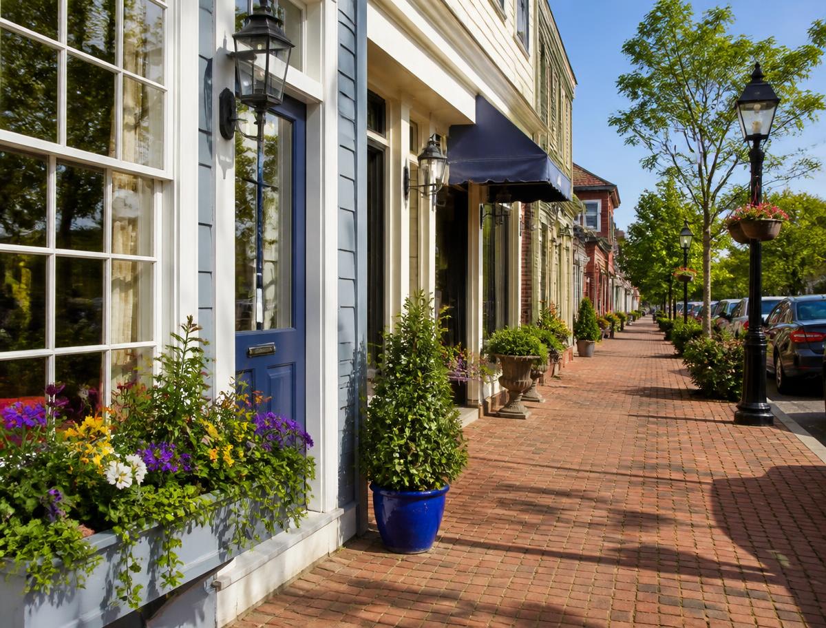 Historic downtown storefronts painted in soft coastal colors along a brick sidewalk